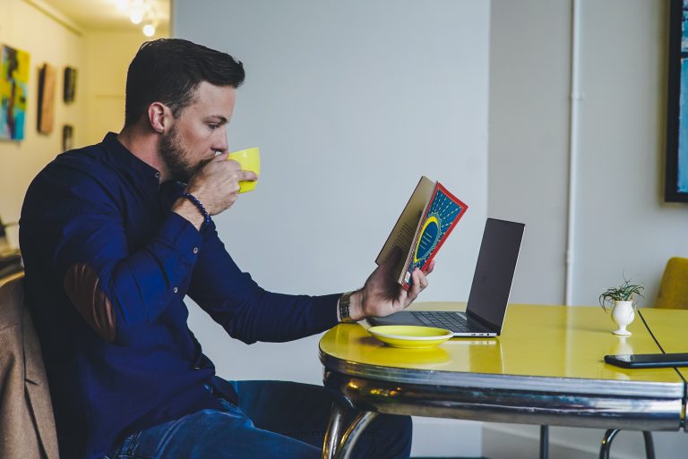 man reading books at laptop